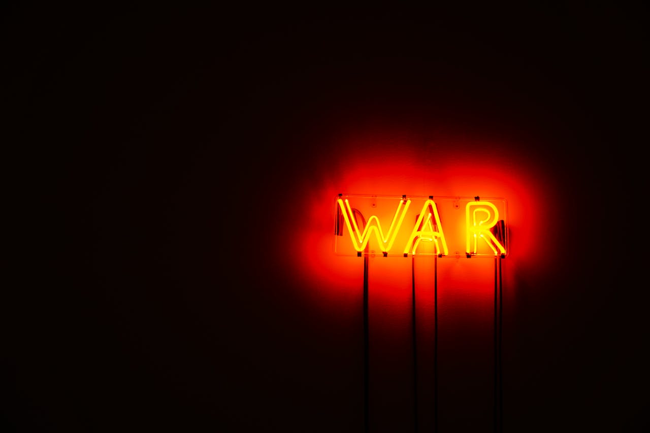 Bright neon WAR sign illuminating a dark space, conveying a strong message.